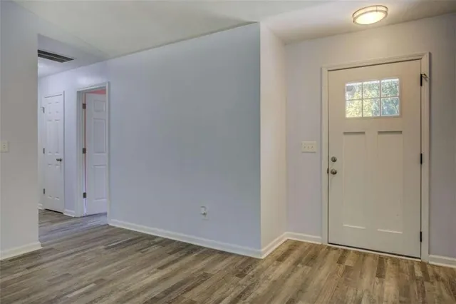 an empty room with wooden floor and fan