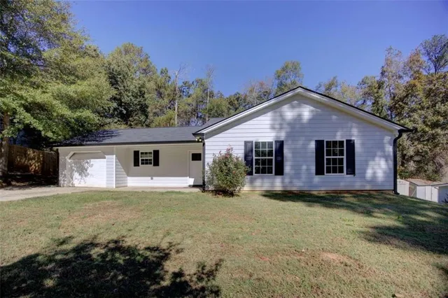 a front view of house with yard and trees in the background