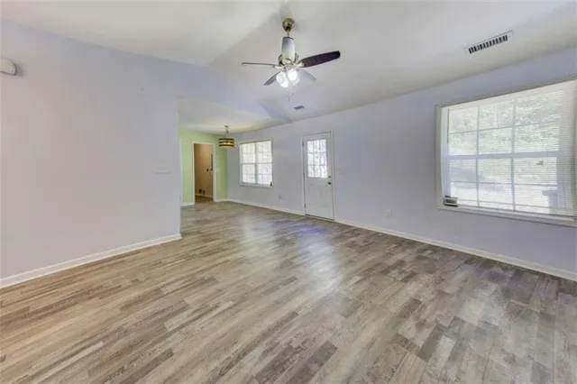 a view of empty room with wooden floor and ceiling fan