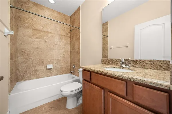 a bathroom with a granite countertop bathtub shower sink vanity and toilet