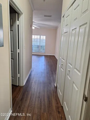 a view of an empty room with wooden floor and a ceiling fan