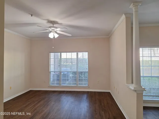 a view of an empty room with wooden floor and a window