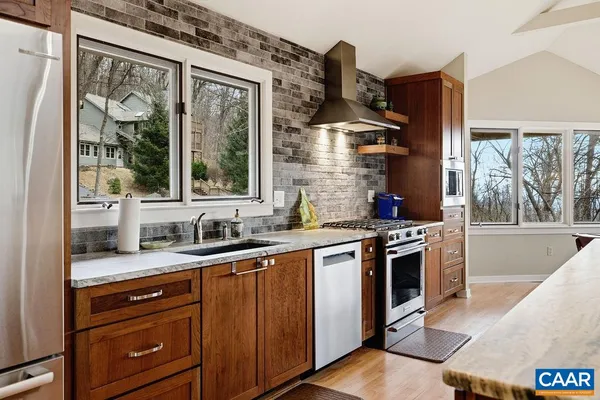 a kitchen with stainless steel appliances granite countertop a sink stove and wooden cabinets