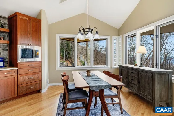 a dining room with wooden floor a chandelier a wooden table and chairs
