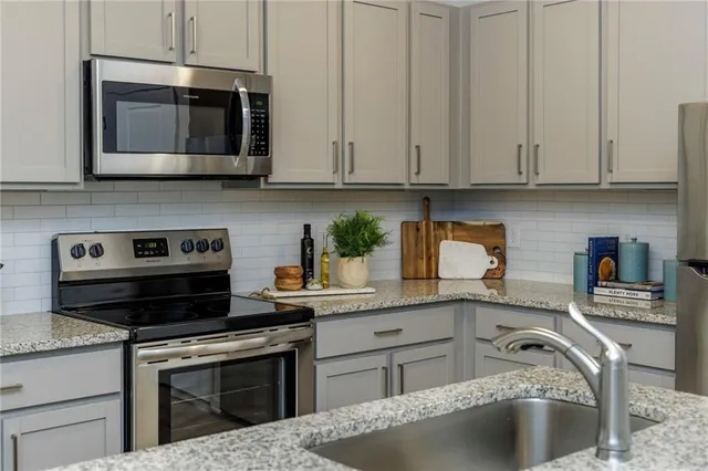 a kitchen with granite countertop white cabinets stainless steel appliances and a sink