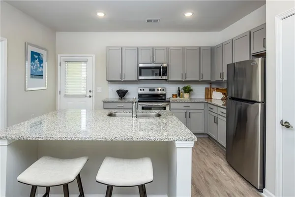 a kitchen with stainless steel appliances granite countertop a sink a stove a refrigerator cabinets and a dining table