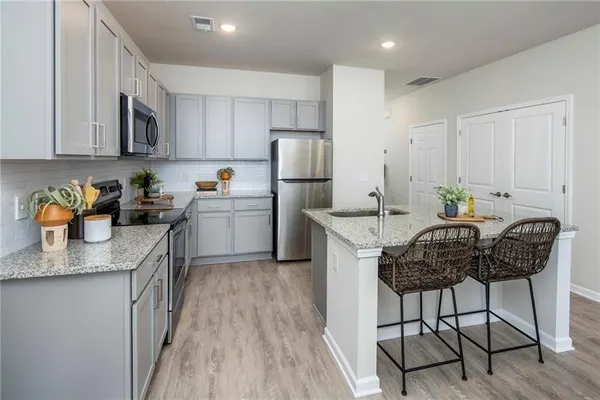 a kitchen with stainless steel appliances granite countertop a table chairs sink and cabinets