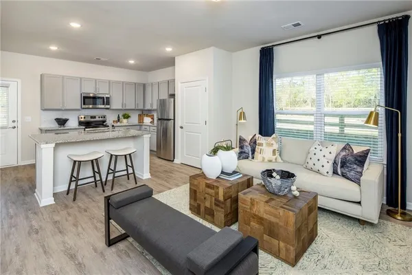 a living room with furniture kitchen view and a large window
