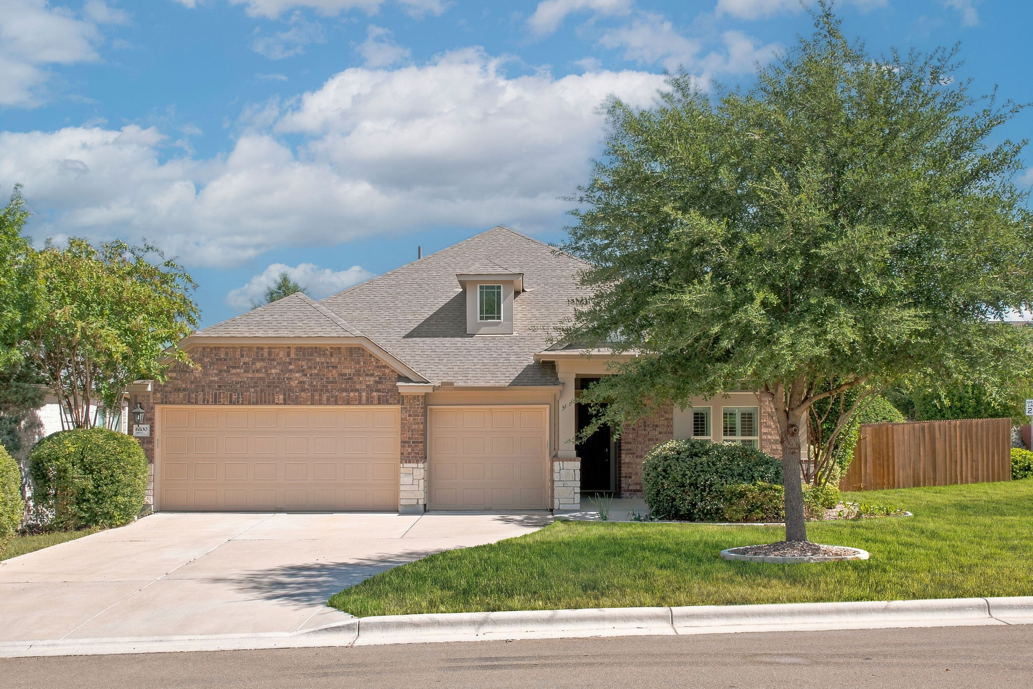 Classic brick and stone architecture pairs with manicured lawns and a spacious front-load garage.