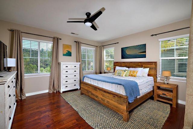 a bedroom with a large bed a flat tv screen and a dresser