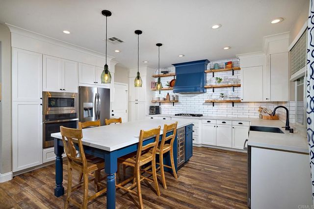 a kitchen with stainless steel appliances kitchen island granite countertop a table chairs microwave and sink