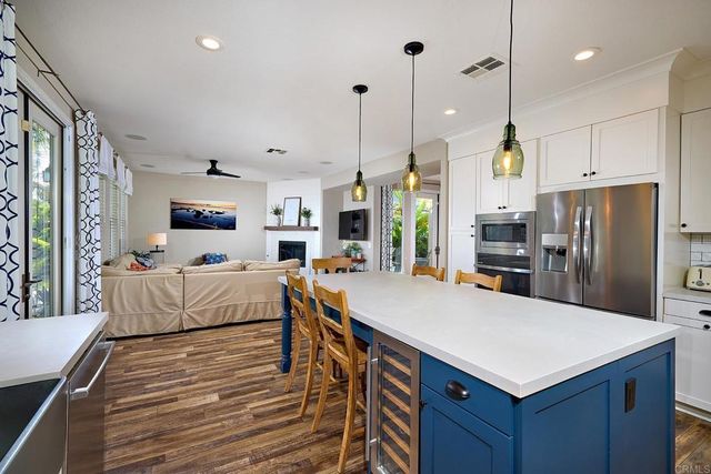 a large kitchen with stainless steel appliances a stove center island a refrigerator and a view of living room