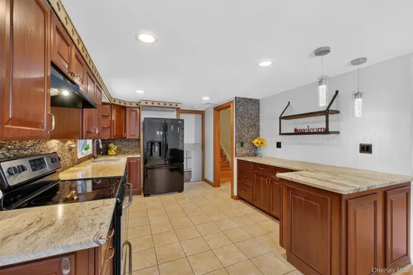 a large kitchen with stainless steel appliances kitchen island granite countertop a large counter top a stove a sink dishwasher and a refrigerator with wooden floor
