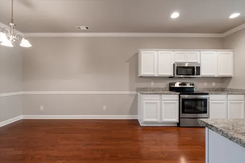 a kitchen with granite countertop white cabinets and black stainless steel appliances