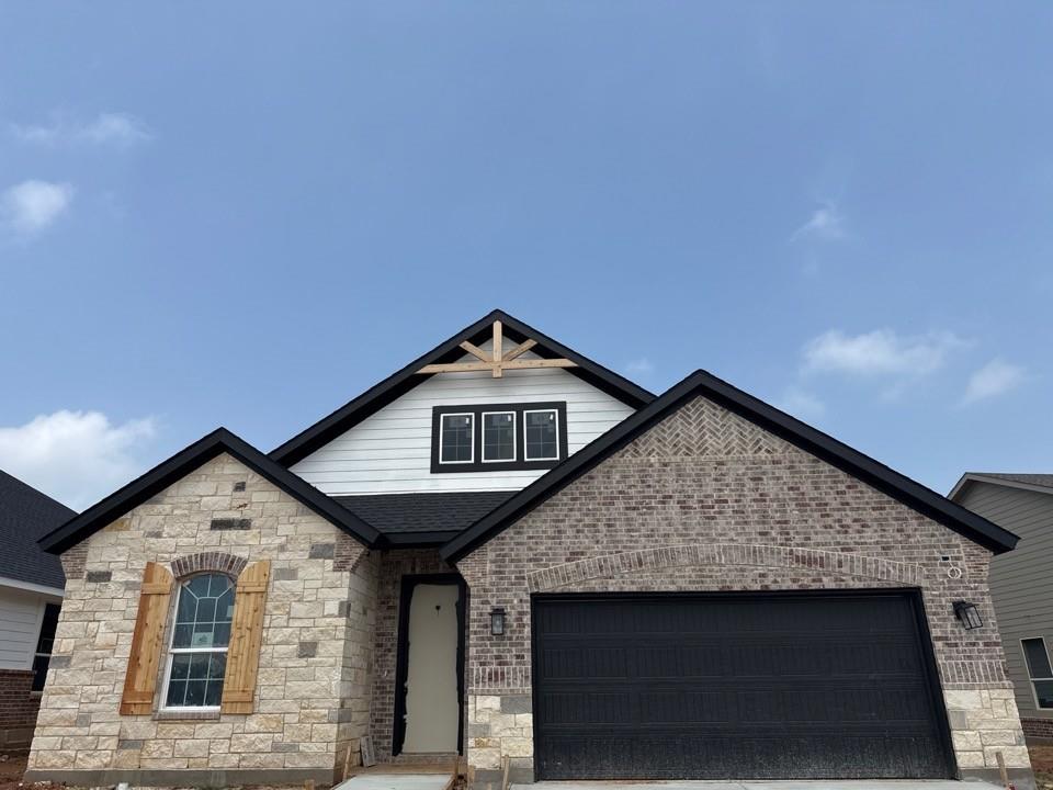 Stone and brick facade featuring an arched window with wood shutters