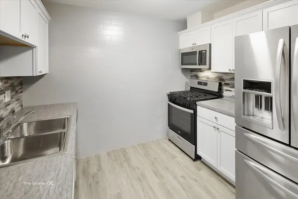 a kitchen with stainless steel appliances a stove microwave and sink