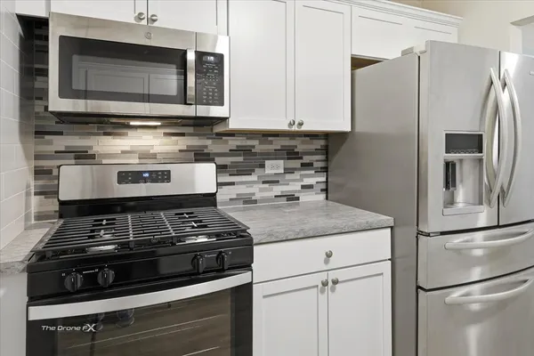 a kitchen with stainless steel appliances granite countertop a stove microwave and refrigerator