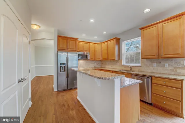 a kitchen with kitchen island granite countertop wooden floors and stainless steel appliances