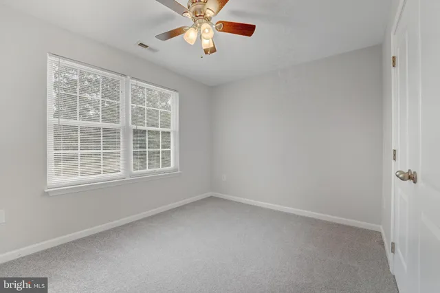 an empty room with a window and a fan