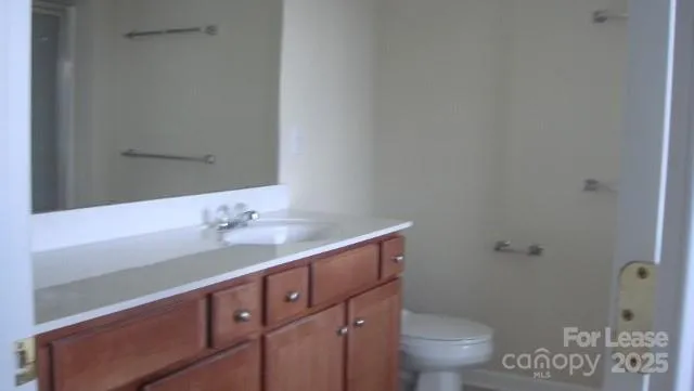 a bathroom with a granite countertop sink a toilet and a mirror