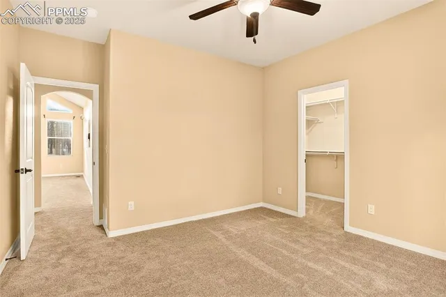 an empty room with closet and a chandelier fan