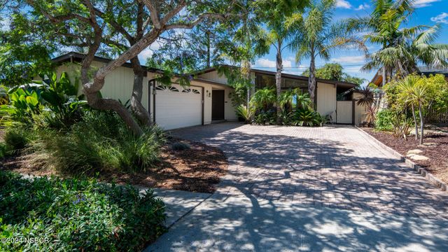 a front view of a house with a tree