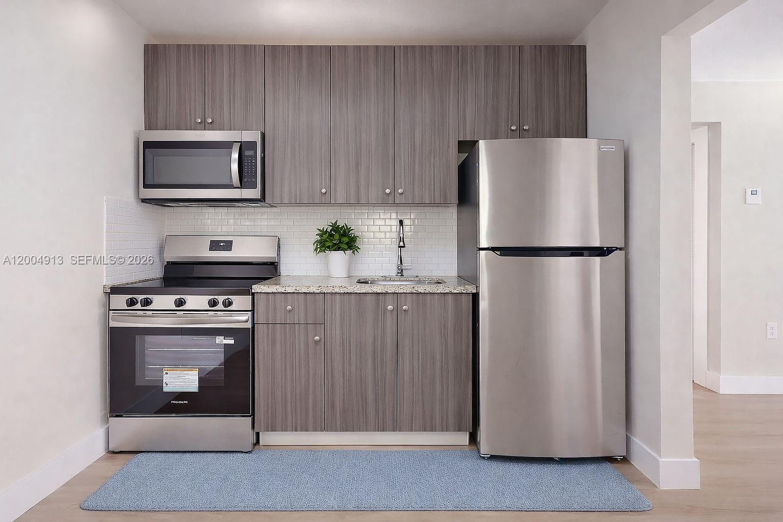567 Southwest 3rd Street, Unit 2 Miami, FL 33130 - Photo 12 of 29 a white refrigerator freezer and a stove sitting inside of a kitchen with granite countertop wooden cabinets