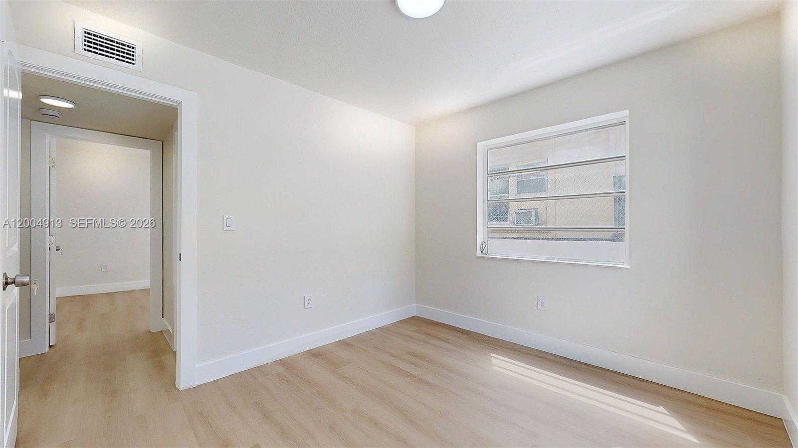 567 Southwest 3rd Street, Unit 2 Miami, FL 33130 - Photo 27 of 29 an empty room with wooden floor and windows