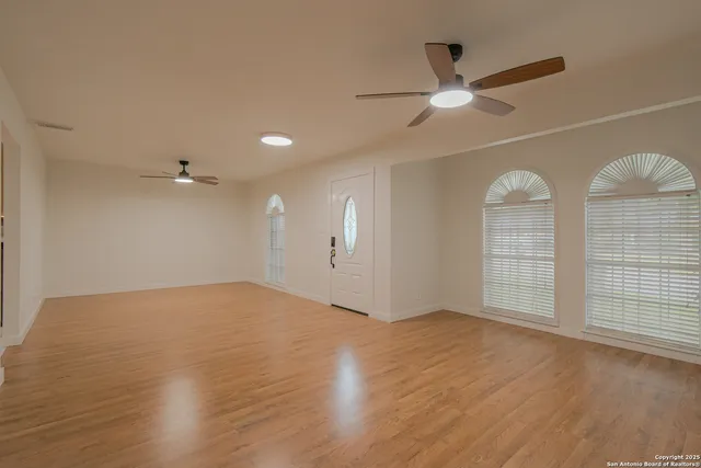 an empty room with wooden floor and windows