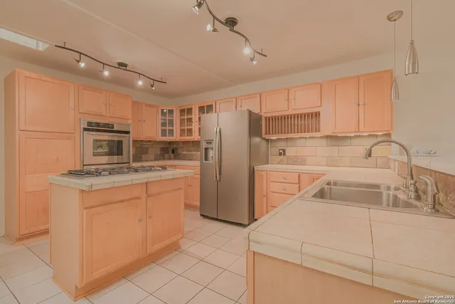 a kitchen that has a sink cabinets stainless steel appliances and a counter top space