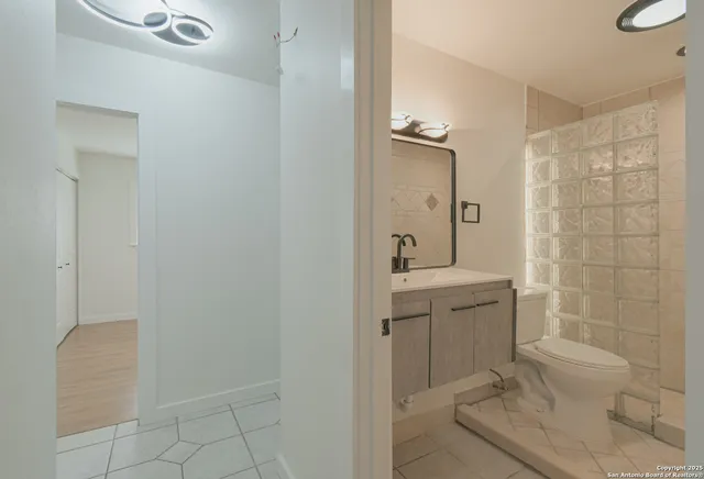 a view of a hallway with wooden floor and a bathroom
