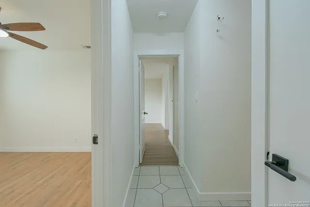a view of empty room with wooden floor and fan