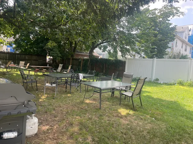 a view of swimming pool with table and chairs potted plants and large tree