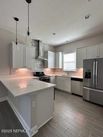 a kitchen with stainless steel appliances kitchen island granite countertop a refrigerator a sink dishwasher a oven with white cabinets and wooden floor