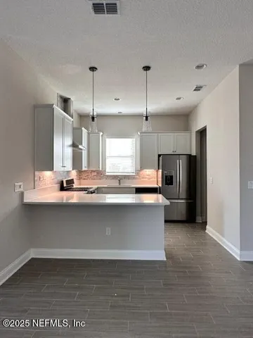 a large kitchen with stainless steel appliances a large counter top a stove a refrigerator and a sink