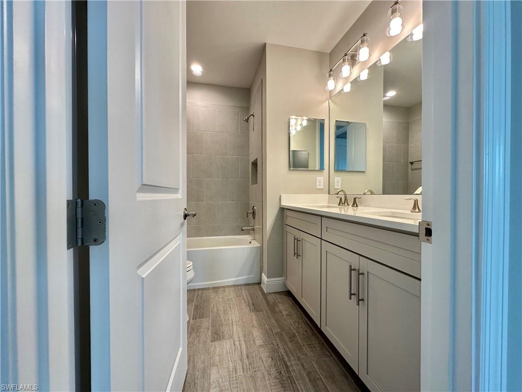 4580 Centaurus Circle Naples, FL 34120 - Photo 14 of 25 Bathroom with double vanity, dark wood-style floors, and shower / washtub combination