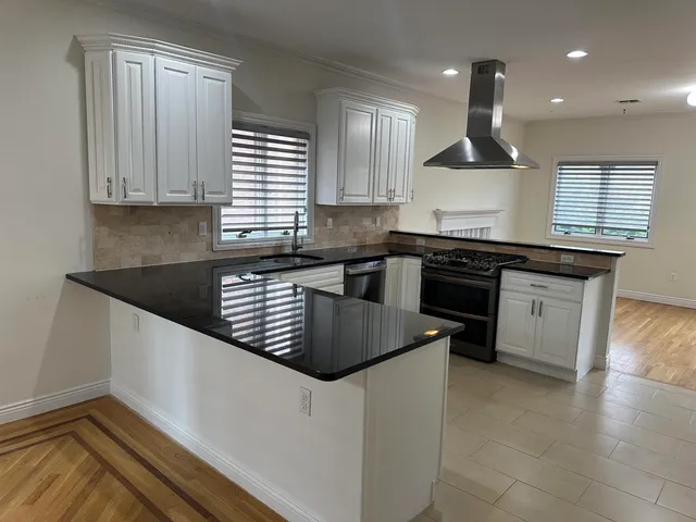 a kitchen with granite countertop a sink a stove and cabinets