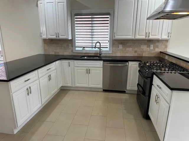 a kitchen with granite countertop a sink a stove and cabinets