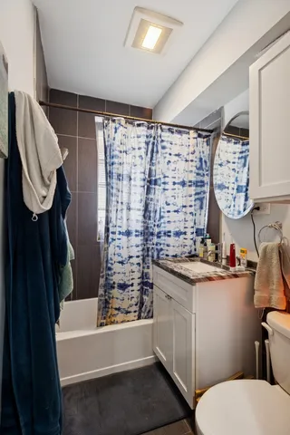 a bathroom with a granite countertop toilet sink and mirror