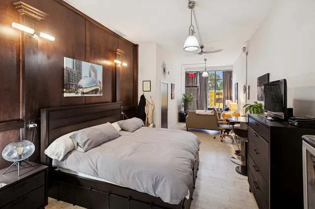 a bedroom with a bed desk and flat screen tv