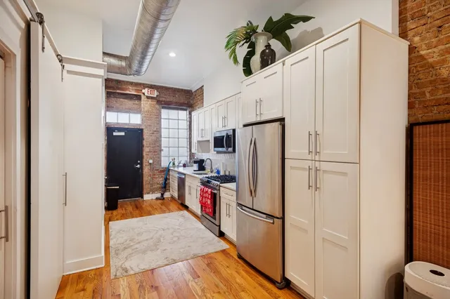 a kitchen with stainless steel appliances a refrigerator a stove a sink a washer dryer and white cabinets