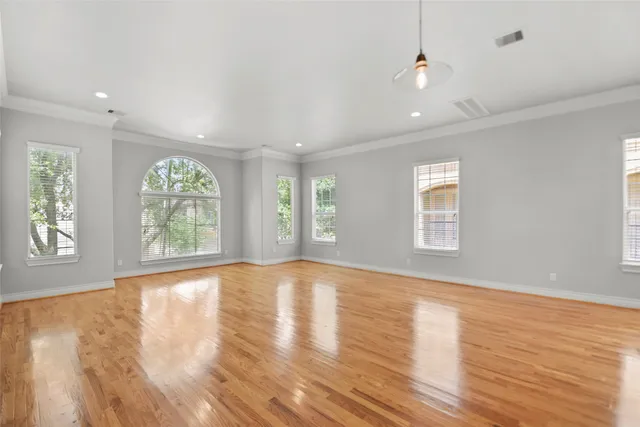a view of empty room with wooden floor and a window