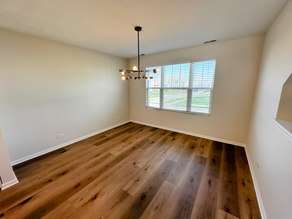 208 Goldenrod Drive, Unit 1 Elgin, IL 60124 - Photo 6 of 17 wooden floor in an empty room with a window