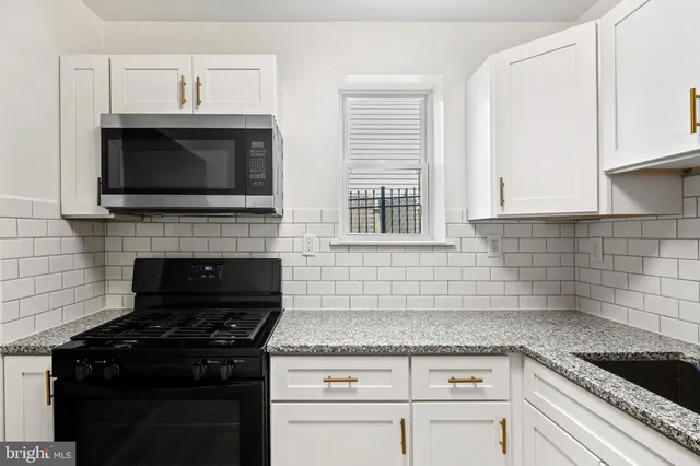 a kitchen with granite countertop white cabinets and black appliances