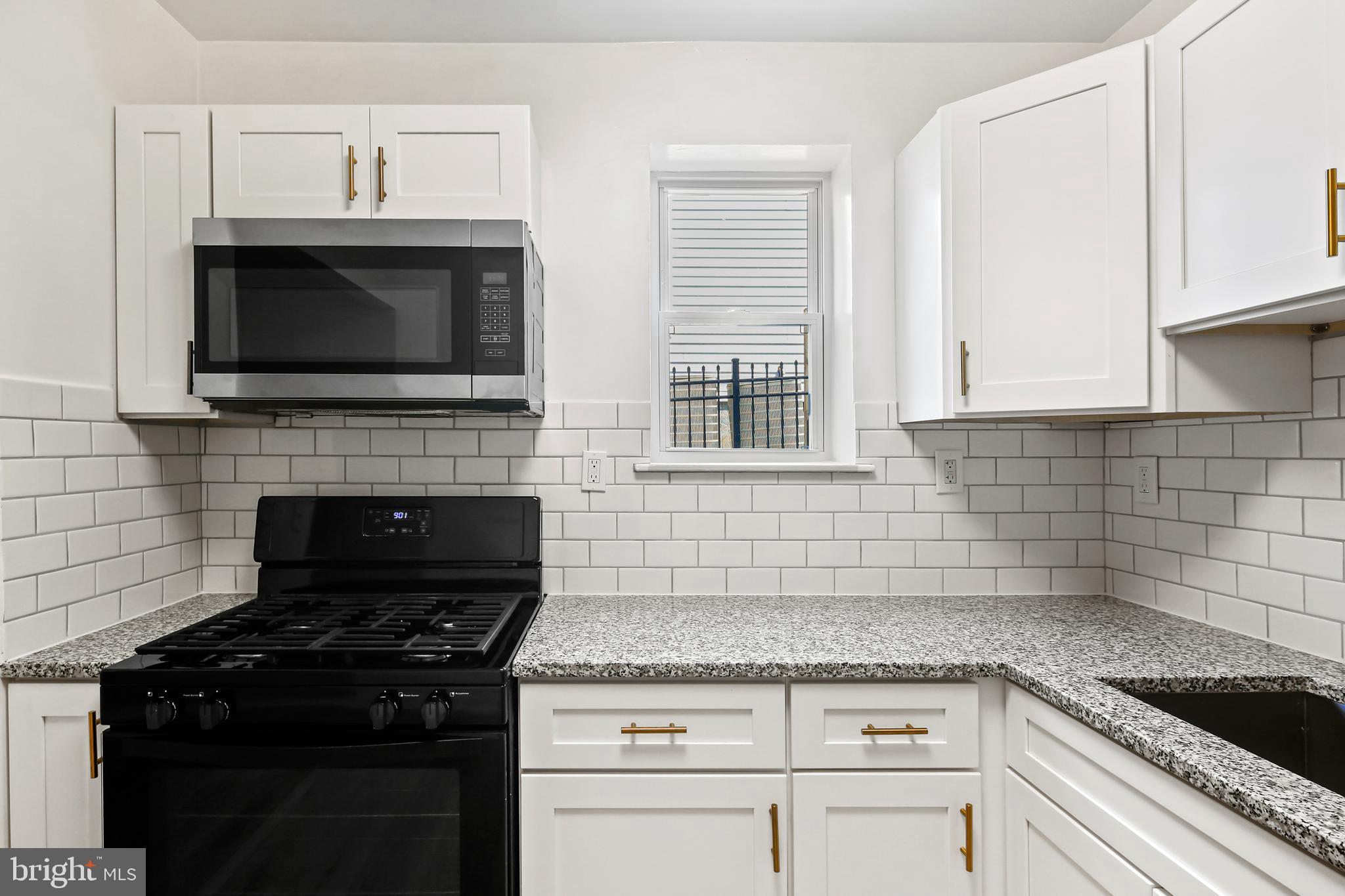 a kitchen with granite countertop white cabinets and black appliances