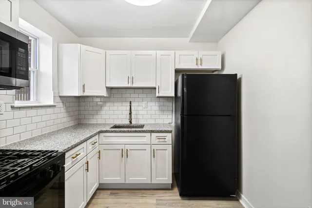 a kitchen with a sink a refrigerator and cabinets
