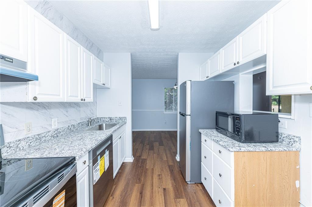 2398 Lawrenceville Highway, Unit U Decatur, GA 30033 - Photo 12 of 32 a kitchen with stainless steel appliances granite countertop a refrigerator a stove and a sink with wooden floor