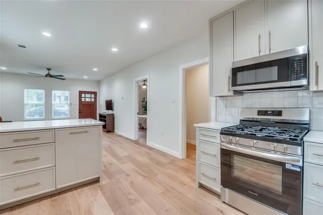 a kitchen with stainless steel appliances white cabinets and a stove top oven