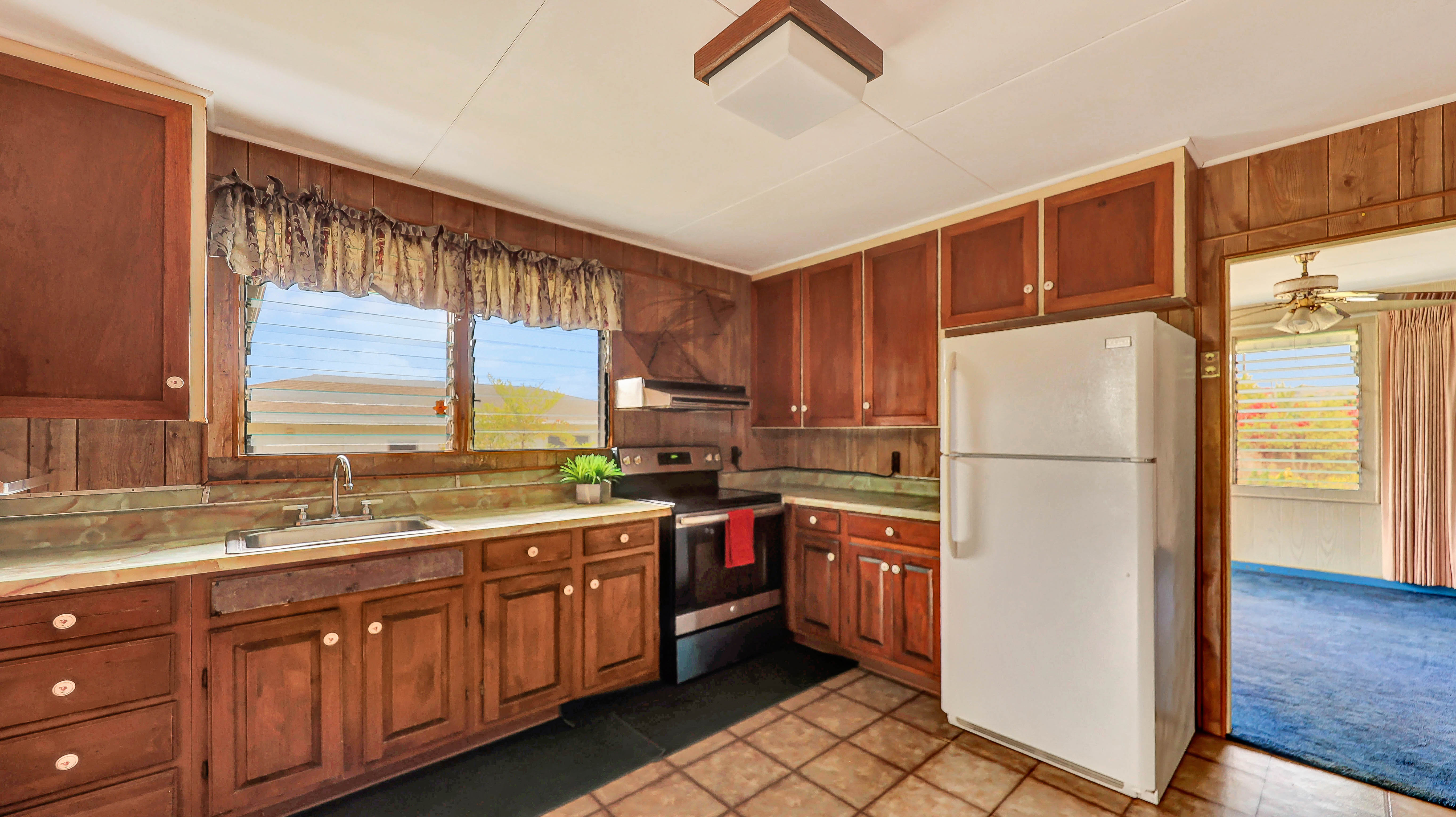 5116 Kula Road Kapaa, HI 96746 - Photo 8 of 28 a kitchen with stainless steel appliances granite countertop a refrigerator a sink dishwasher a stove with white cabinets and wooden floor