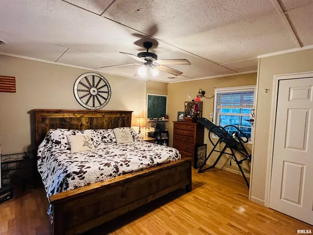 a bedroom with a bed and dresser with wooden floor